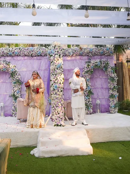 A beautiful moment of the couple on their wedding stage. The lavender and white floral decor perfectly complements their elegant attire, creating a picture-perfect memory.