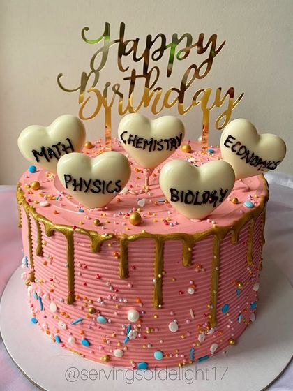 A quirky and fun cake for a student or teacher, decorated with white chocolate hearts representing different school subjects like Math, Physics, and Chemistry.