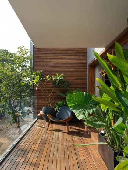 A private, wood-decked balcony becomes a tranquil escape amidst the city. Lined with a timber-clad wall and filled with lush plants, it serves as a perfect spot for quiet contemplation.