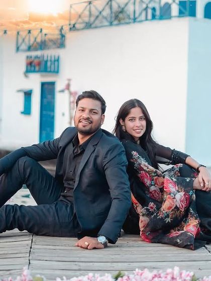 A relaxed and happy portrait at the Santorini-themed set. The couple sits by the water, creating a calm and romantic vacation vibe.