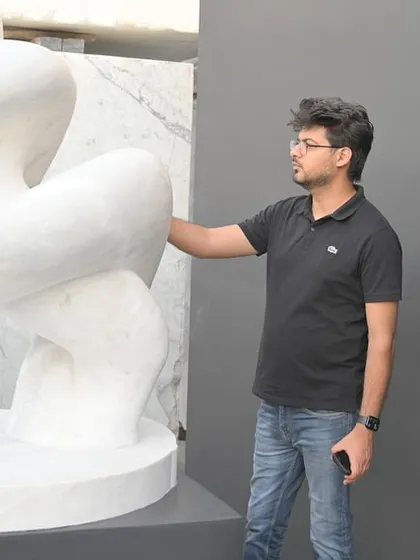 Kunal examining the smooth, curved lines of a contemporary marble art piece.