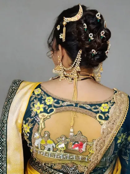 A detailed view of the bridal bun adorned with a 'chandrakor' hair accessory and other traditional pieces, complementing her blouse's 'doli' embroidery.