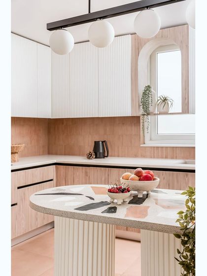 The kitchen in the "Marshmallow" penthouse features a central island with a Venetian terrazzo countertop and a graceful linear chandelier.