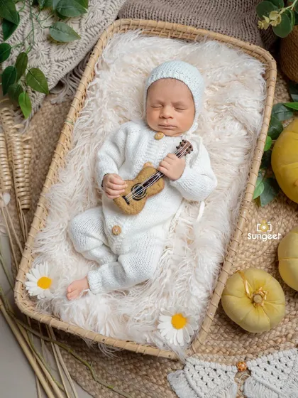 A close-up of our little musician in a cozy basket. The neutral tones of the knit outfit and the rustic feel of the basket create a warm, organic portrait.