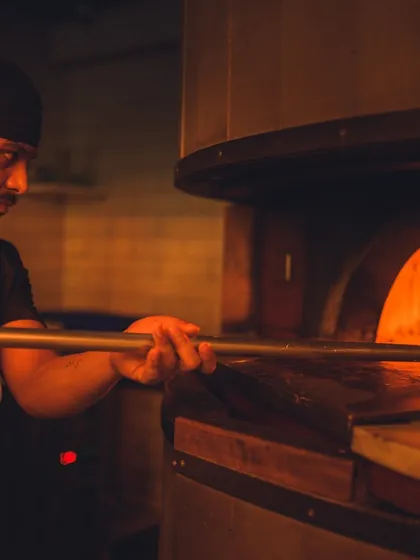 The heart of our kitchen. Our pizzaiolo carefully tends to a pie in the wood-fired oven, where temperatures get hot enough to cook a Neapolitan pizza in just 60 to 90 seconds.