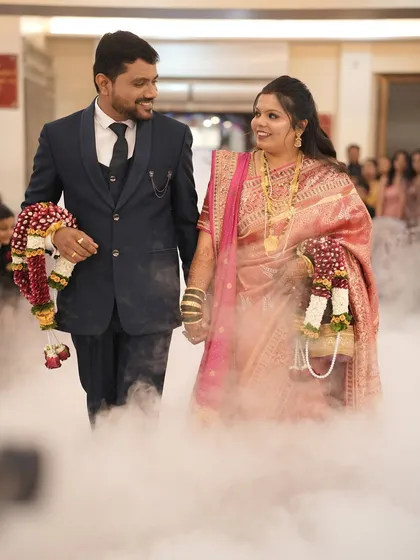 A happy moment captured during the reception entrance. The bride's soft makeup complements her traditional pink silk saree.