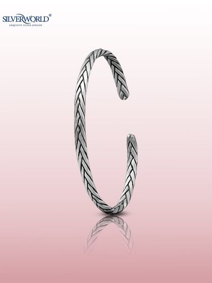 A minimalist open cuff bangle with a braided or 'herringbone' pattern. This oxidized silver piece has a modern, understated appeal.