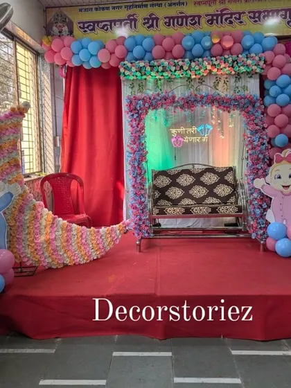 A beautiful setup for a traditional naming ceremony or 'Barsa'. The centerpiece is a decorated jhula (cradle) on a staged platform, framed by balloons and adorable baby cutouts, creating a memorable spot for this important occasion.