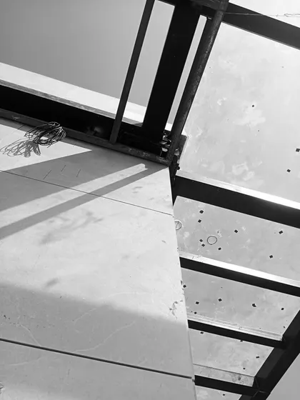 A close-up detail of the terrace canopy construction, revealing the joinery and raw materials of the steel and panel framework.