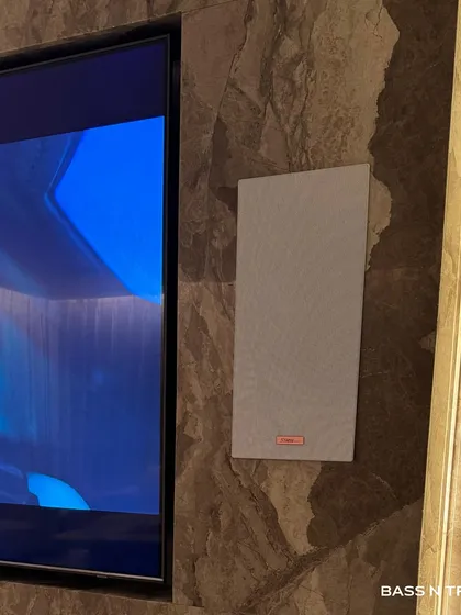 A close-up of a Starke Sound in-wall speaker, which sits nearly flush against the marble wall. This is the ideal solution for high-end sound that doesn't interfere with your interior design.