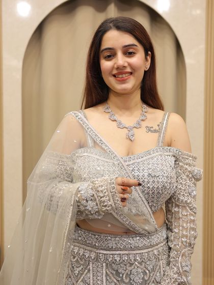 A client trying on a beautiful silver-grey lehenga in our store. Her smile shows the joy of finding the perfect outfit.