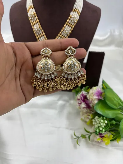 A close-up of the 'Indira' set's earrings, showcasing the delicate enamel and pearl work.