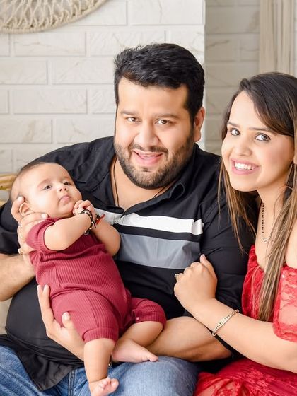 A bright and happy family photo with their new baby. The parents are all smiles in this relaxed portrait, taken on the rattan sofa in our versatile boho studio set.