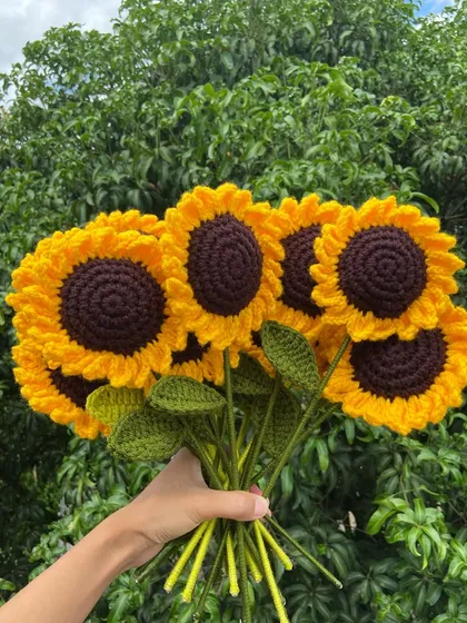 A fresh bouquet of my bestselling crochet sunflowers, held up against the natural greenery of my home in Nagaland. Each sunflower is crafted with detailed petals and a rich brown center.