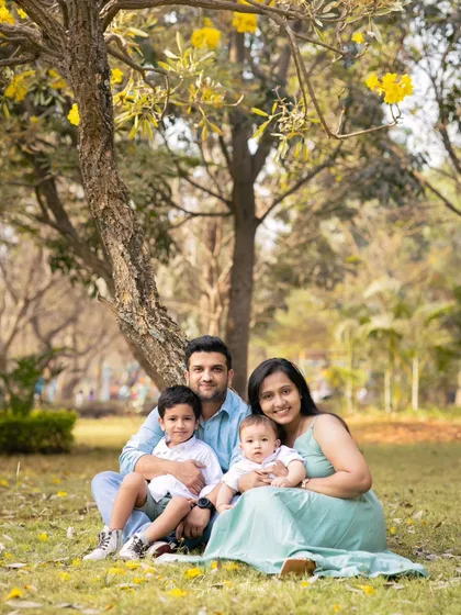 A lovely outdoor family portrait under a tree with beautiful yellow flowers, capturing a perfect family moment.