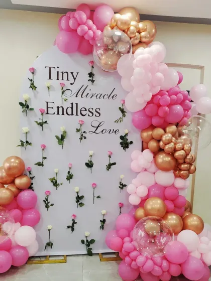 For a beautiful baby girl's celebration, this pink and rose gold balloon arch is a fantastic choice. The backdrop, with its "Tiny Miracle Endless Love" message and scattered roses, adds a sweet and personal touch to the baby shower decor.