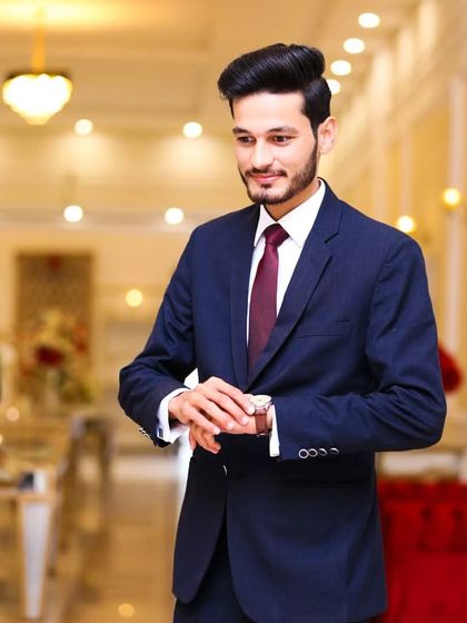 A stylish groom in a navy blue suit, perfect for an engagement or reception. The watch and tie are key accessories that complete the look.