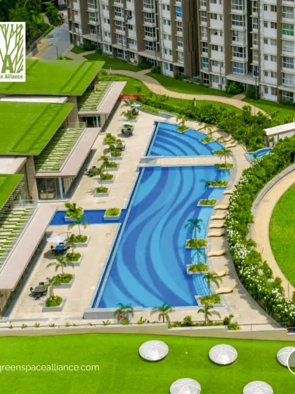 This aerial view shows a resort-style swimming pool and clubhouse with green roofs, adjacent to a full-sized cricket ground. This combination of amenities in a residential development showcases our ability to design for a diverse range of recreational and lifestyle needs.