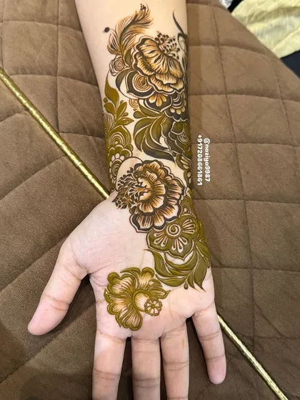 The completed small floral trail on the hand and wrist. It's a beautiful, self-contained design that is both elegant and eye-catching.