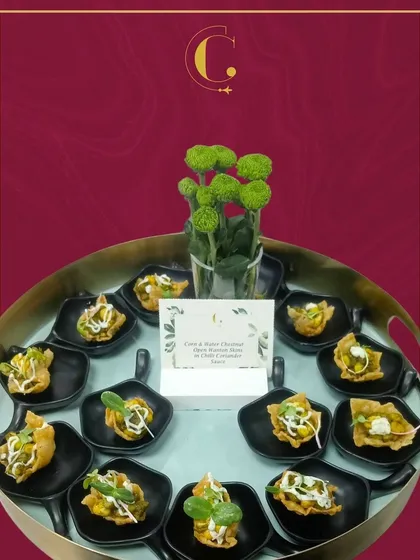 A tray of Corn & Water Chestnut Wontons, tossed in a zesty chilli coriander sauce. These appetizers offer a delightful combination of crunch, sweetness, and heat.