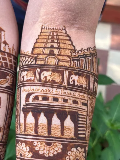 A detailed shot of the temple and meeting spot motifs. The design captures the exact location where the couple's journey began, making it a cherished part of their mehendi.