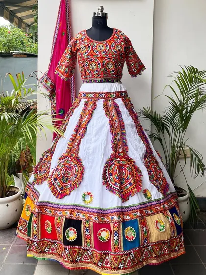 The full view of this beautiful white lehenga. The skirt features colorful embroidered patches and a multi-colored border.