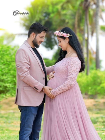 A quiet, intimate moment between an expecting couple. The soft pink tones of her lace gown and his blazer are beautifully coordinated for this romantic outdoor pregnancy shoot.