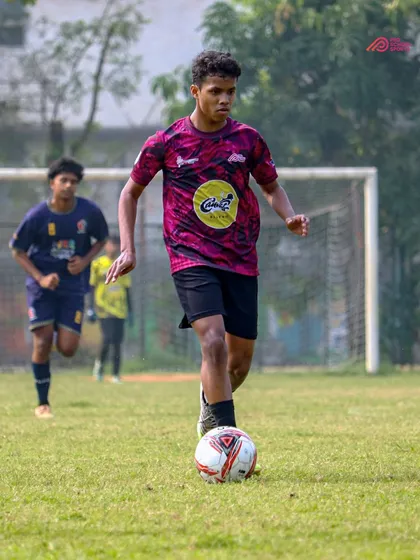 With eyes on the goal, our player advances the ball up the field during a crucial match.