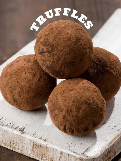 Classic chocolate truffles, simply presented on a white board. The dusting of cocoa powder is the key detail that makes them look authentic and rich.