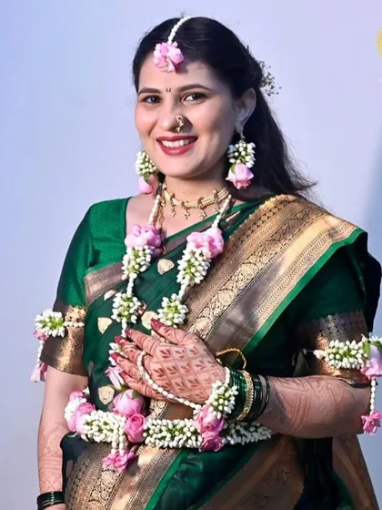 A smiling portrait of the mom-to-be, showing off her complete floral jewellery set, including the hathphool and kamarband.