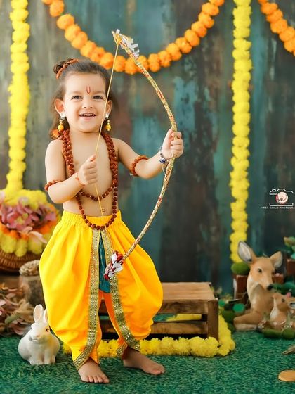 Celebrating culture with a 'Little Ram' photoshoot. This toddler looks joyful and strong, dressed in traditional attire and holding a bow and arrow, set against a vibrant, festive backdrop.