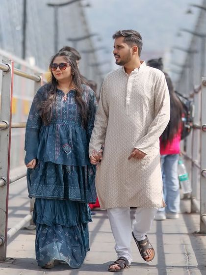 A candid shot of the couple walking hand-in-hand across the bridge. Their traditional attire and the natural interaction make this a beautiful, authentic photo.