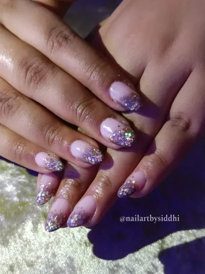 A festive Diwali look featuring a nude base with a heavy cascade of holographic glitter from the tips.