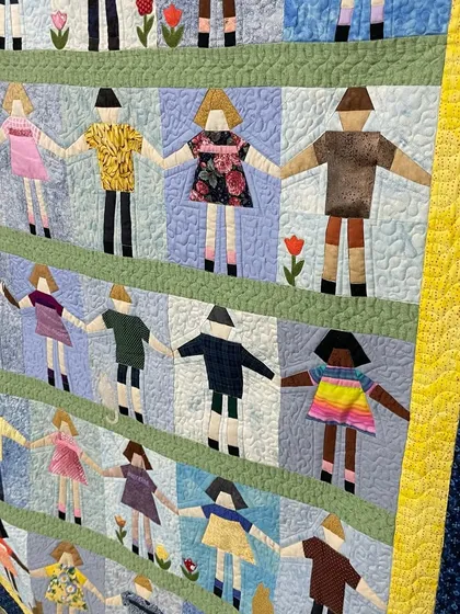 A "Paper Doll" quilt, with charming appliquéd figures holding hands. Our quilting adds texture to the background and clothes.