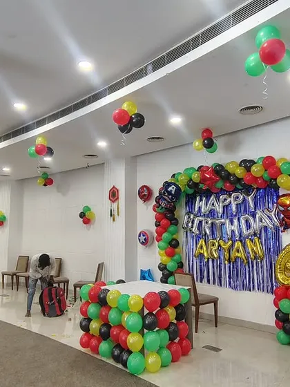 Transforming a large hall for Aryan's 6th birthday with a superhero theme. The setup includes a balloon arch backdrop with a Spiderman foil balloon and balloon bunches scattered across the ceiling to fill the space.