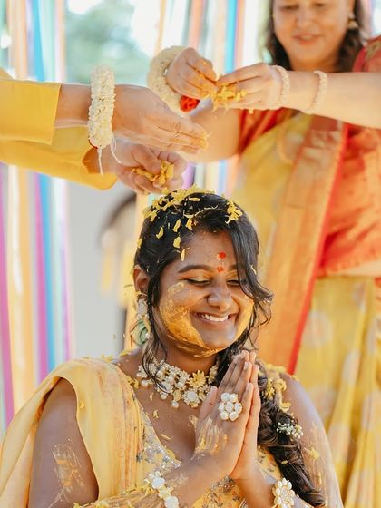 A bride's radiant smile as she is blessed with turmeric paste during her Haldi ceremony.