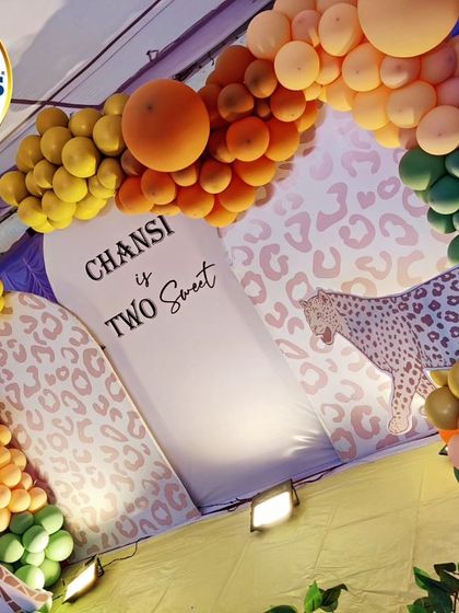 A stylish and modern take on a jungle theme. This setup uses leopard print backdrops and a unique color palette of orange, yellow, and green balloons to create a chic "Two Sweet" safari vibe.