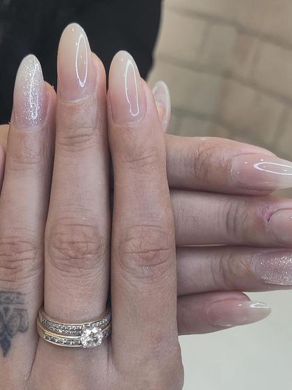 A delicate and ethereal look on long almond nails, with a sheer nude base and a subtle dusting of iridescent glitter on the accent nails.