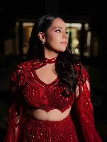 A client looking breathtaking in our crimson red lehenga, paired elegantly with a flowing cape for her Roka ceremony.
