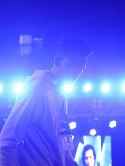 A candid shot of a student enjoying the music under the blue stage lights.