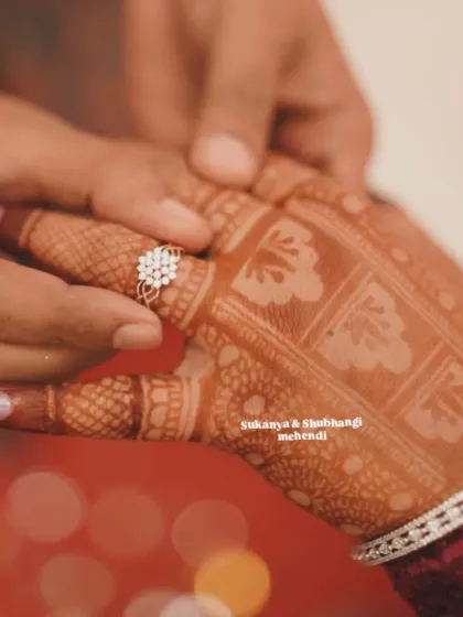 A symbolic and emotional moment of the ring ceremony, with the groom placing the ring on the bride's mehendi-covered finger.