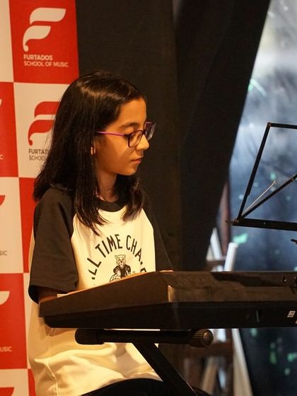 A young pianist concentrates on her piece during the Chembur Musical Showcase. Our piano curriculum, based on global standards, prepares students for both exams and expressive performances.