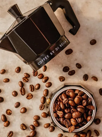 A creative flat-lay of a moka pot and coffee beans. The deconstructed arrangement is visually interesting and tells the story of the coffee-making process in a stylish, modern way.
