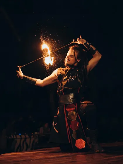 A moment of quiet intensity. This artist is performing with fire poi, using the spray of sparks to create a magical effect. The costume and pose are part of a larger narrative from one of our fantasy-themed shows.