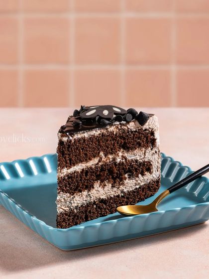 A slice of rich chocolate pastry on a bright blue plate, creating a simple yet striking color contrast.