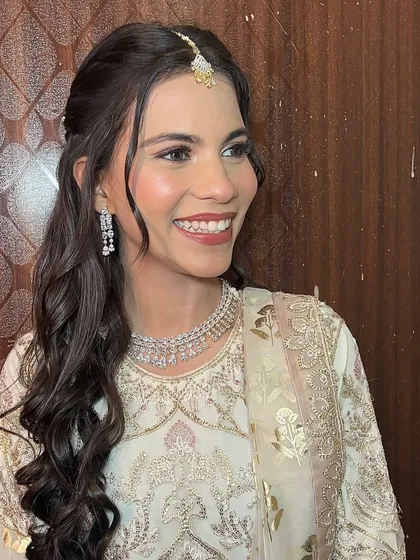 Shining bright in a beautiful white and gold outfit, her makeup features a dewy base and defined eyes.