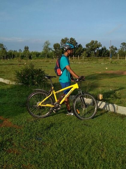 A cyclist with his bright yellow mountain bike, enjoying the open green fields on a sunny weekend ride.