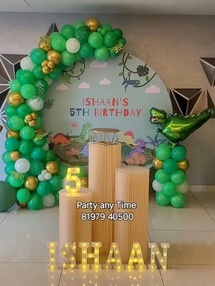 The main stage for the dinosaur theme, complete with foil dinosaur balloons, a custom backdrop, and light-up letters.