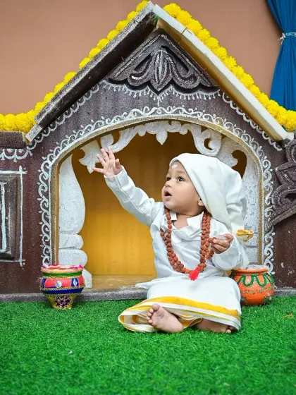 A wider view of the Sai Baba themed set, showing the little devotee in a beautiful, rustic temple setting. His upward glance adds a sense of wonder and devotion to the portrait.