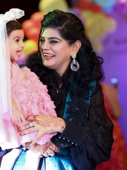 The joy on a woman's face as she holds the little birthday girl, who is looking at her with a sweet expression.